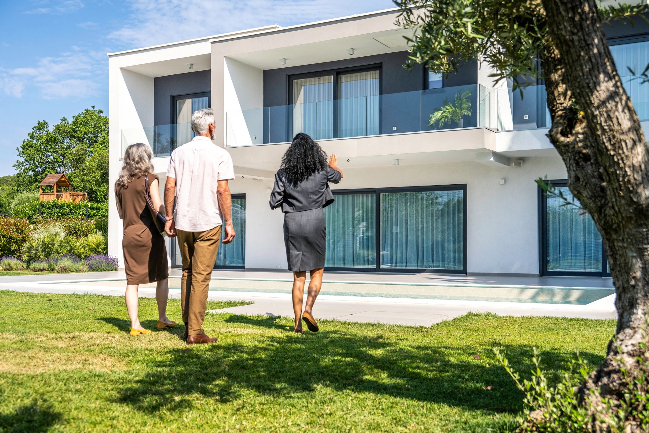 Diverse homeowners meeting with a real estate professional outside a home